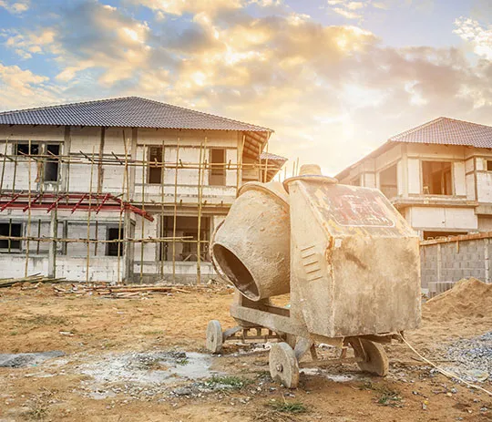 A cement mixer parked in front of a house, ready for construction work.